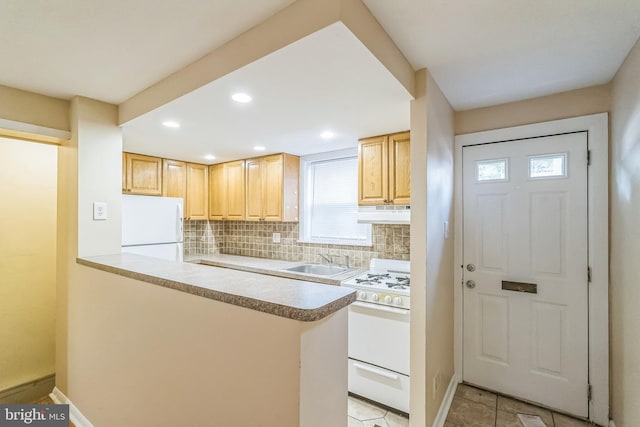 kitchen with tasteful backsplash, light countertops, a sink, white appliances, and under cabinet range hood