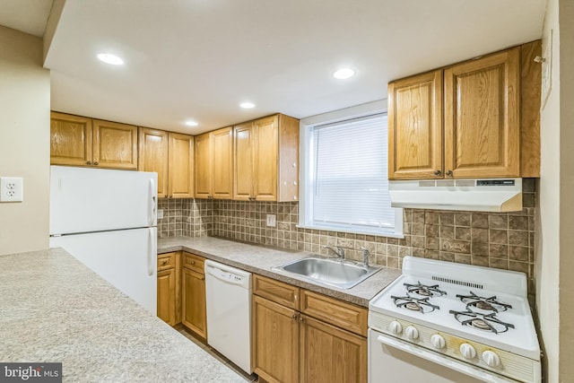 kitchen featuring white appliances, decorative backsplash, light countertops, under cabinet range hood, and a sink