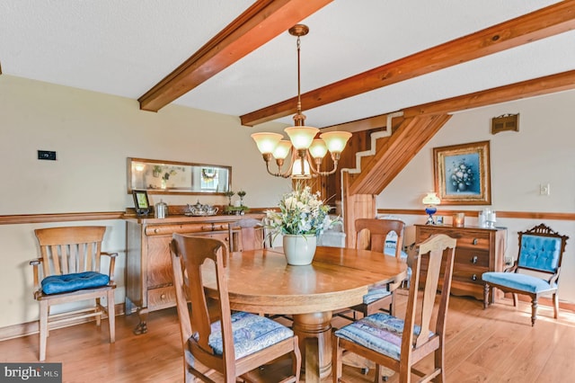 dining area with an inviting chandelier, beamed ceiling, and light hardwood / wood-style flooring