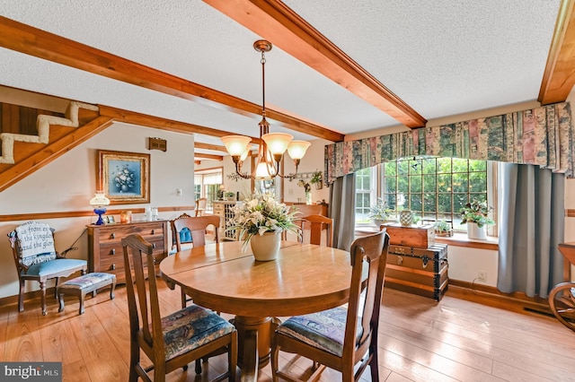 dining room featuring a textured ceiling, beam ceiling, a chandelier, and light hardwood / wood-style floors