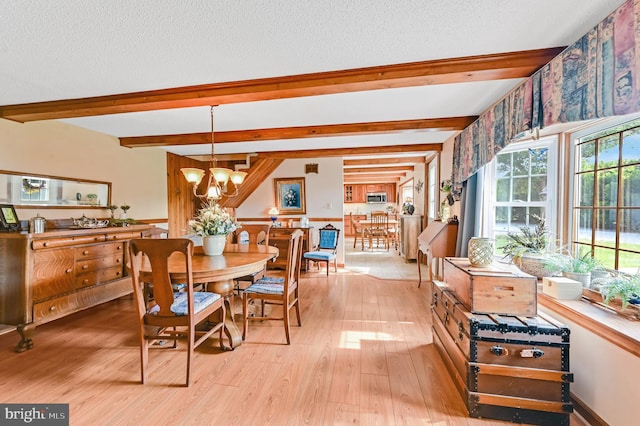 dining space featuring light hardwood / wood-style floors, an inviting chandelier, beam ceiling, and a textured ceiling