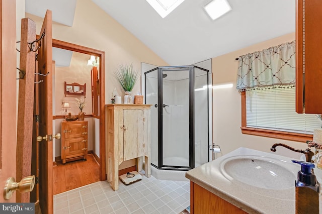 bathroom featuring a shower with door, vanity, wood-type flooring, and lofted ceiling with skylight