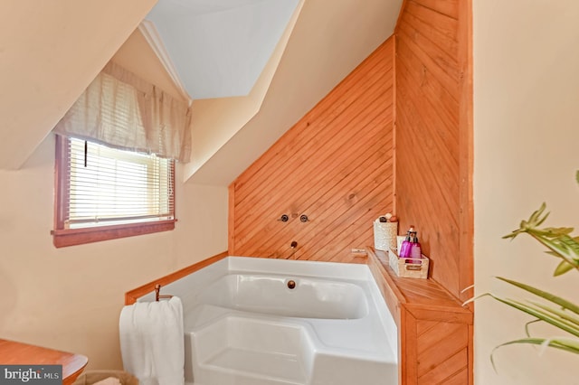 bathroom featuring vaulted ceiling, wood walls, and a washtub