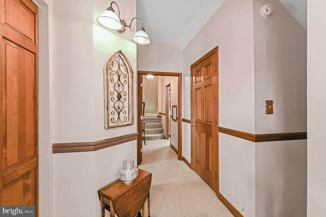 corridor with light carpet and a chandelier