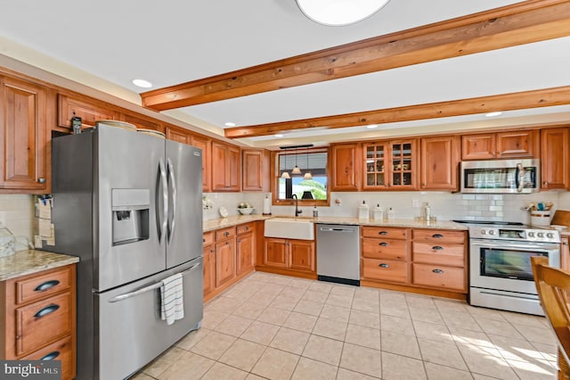 kitchen featuring backsplash, appliances with stainless steel finishes, light stone counters, sink, and beam ceiling