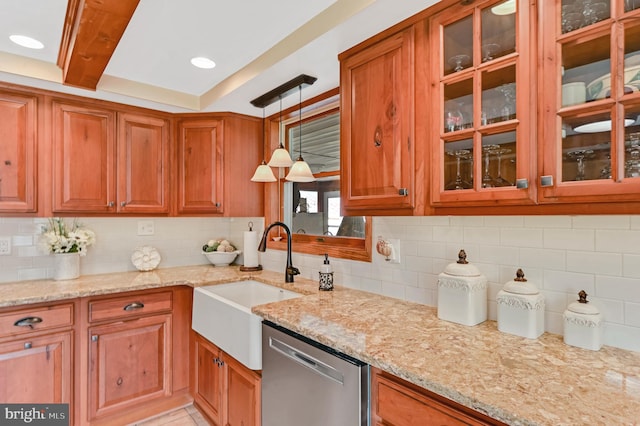 kitchen with hanging light fixtures, dishwasher, sink, light stone countertops, and decorative backsplash