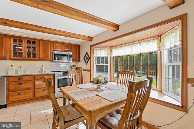 dining space with beamed ceiling and light tile patterned floors