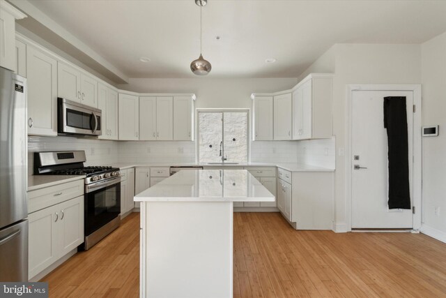 kitchen with a kitchen island, light hardwood / wood-style floors, stainless steel appliances, decorative backsplash, and white cabinets