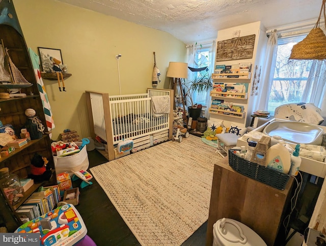 bedroom with a textured ceiling and a nursery area