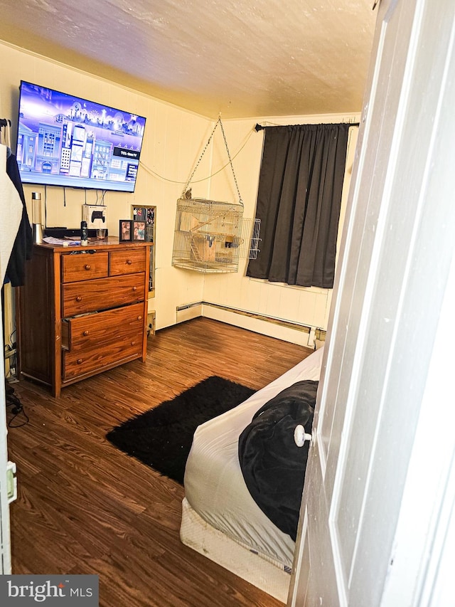 bedroom with a baseboard radiator and dark hardwood / wood-style flooring