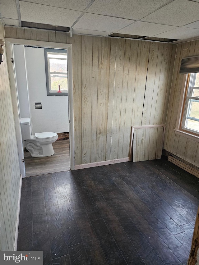 spare room featuring wood walls, a paneled ceiling, plenty of natural light, and dark hardwood / wood-style flooring