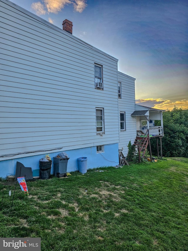 property exterior at dusk featuring a lawn