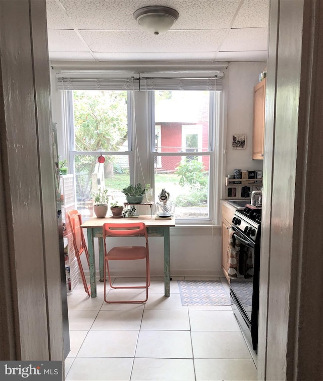 kitchen with a paneled ceiling, a wealth of natural light, black range with gas cooktop, and light tile patterned flooring