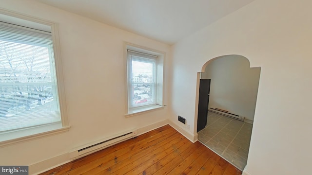 unfurnished room featuring a baseboard heating unit and wood-type flooring