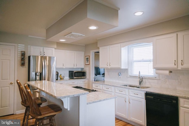 kitchen with sink, a kitchen island, light stone counters, white cabinets, and black appliances