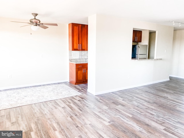 unfurnished living room featuring rail lighting, light hardwood / wood-style flooring, and ceiling fan