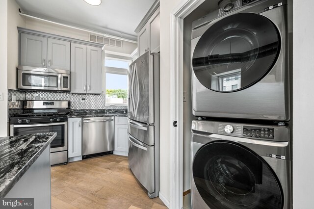 washroom with stacked washer / dryer and light hardwood / wood-style floors