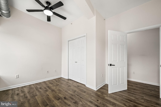 unfurnished bedroom with ceiling fan, a closet, lofted ceiling, and dark wood-type flooring