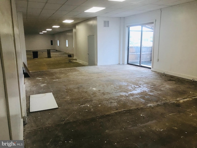 spare room with a drop ceiling, visible vents, and baseboards