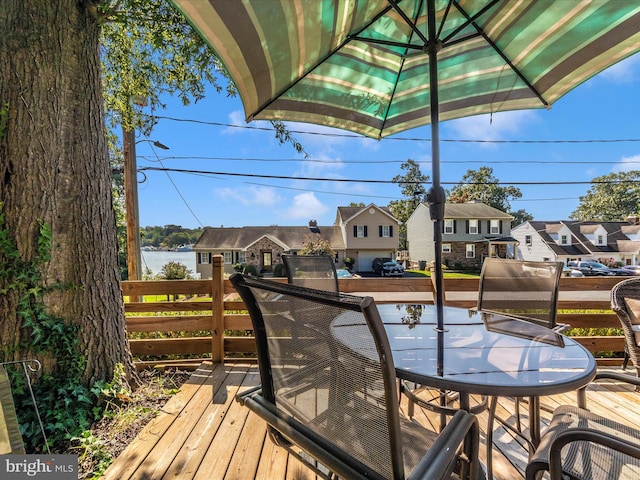 wooden deck featuring outdoor dining space, a water view, and a residential view