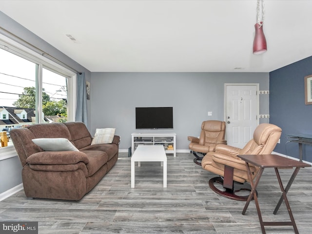 living room featuring visible vents, baseboards, and wood finished floors