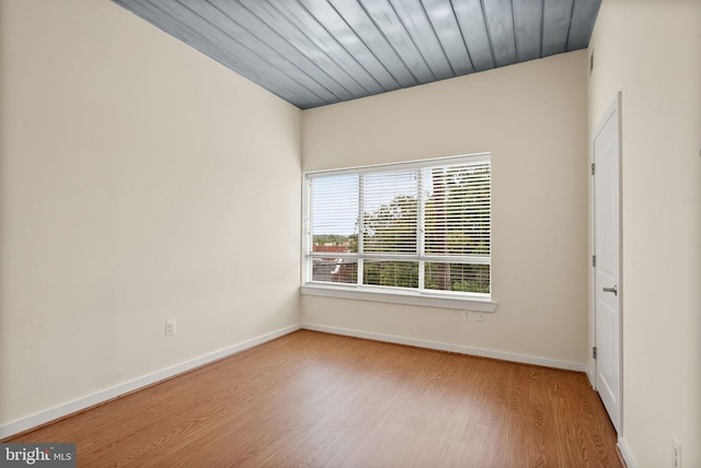 unfurnished room featuring wood finished floors, wood ceiling, and baseboards