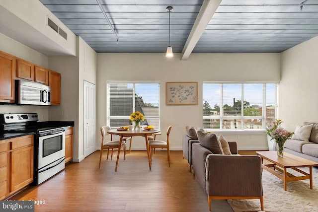 living room featuring light wood finished floors, plenty of natural light, visible vents, and baseboards