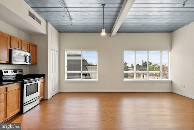 kitchen with light wood finished floors, dark countertops, a wealth of natural light, visible vents, and appliances with stainless steel finishes