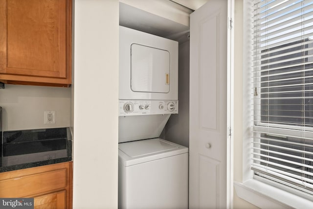 clothes washing area featuring stacked washer and clothes dryer