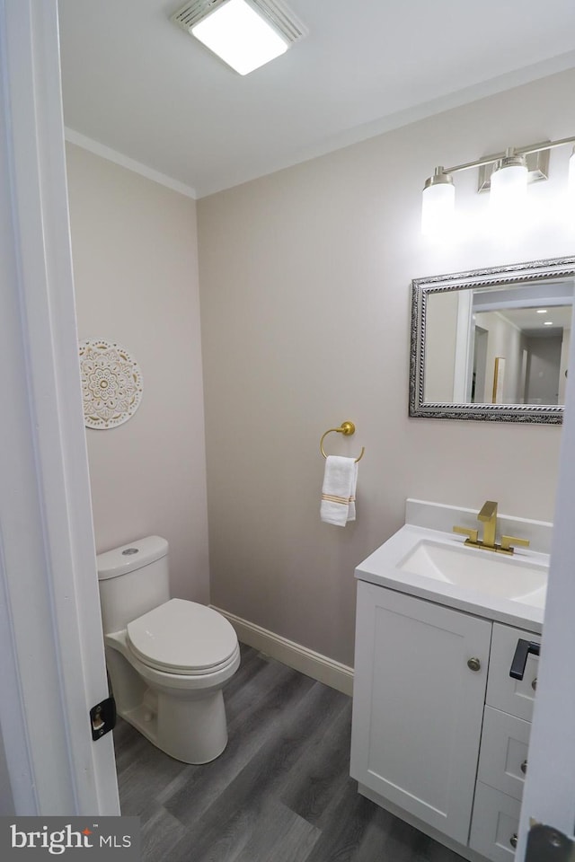 bathroom featuring vanity, toilet, ornamental molding, and hardwood / wood-style floors