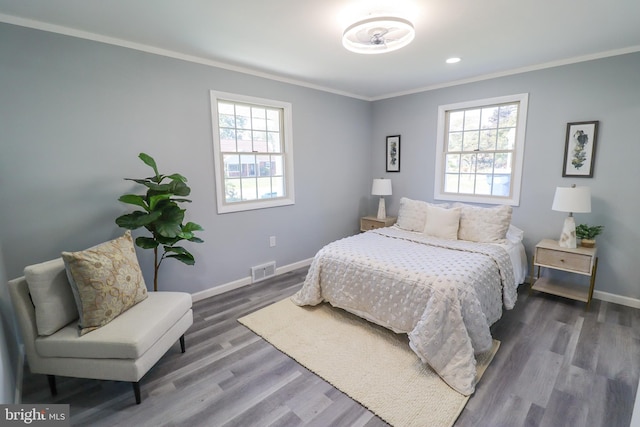 bedroom featuring crown molding, dark hardwood / wood-style floors, and multiple windows