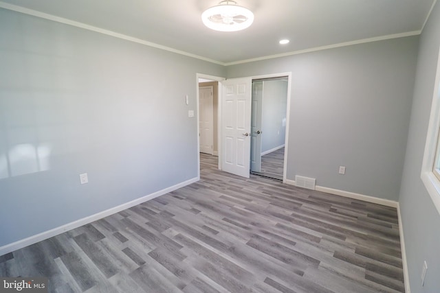 unfurnished bedroom with crown molding, light hardwood / wood-style flooring, and a closet