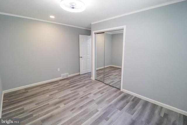 unfurnished bedroom featuring ornamental molding, a closet, and light hardwood / wood-style floors