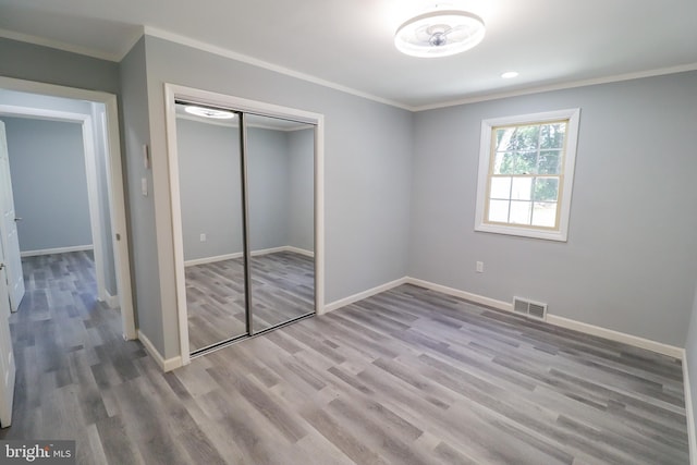 unfurnished bedroom with ornamental molding, a closet, and light hardwood / wood-style floors