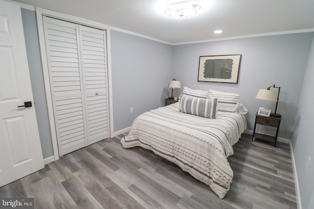 bedroom with a closet, ornamental molding, and hardwood / wood-style floors