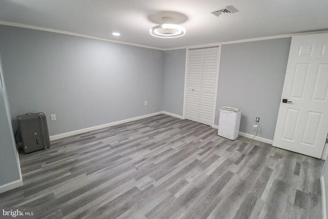 unfurnished bedroom with crown molding, light hardwood / wood-style flooring, and a closet