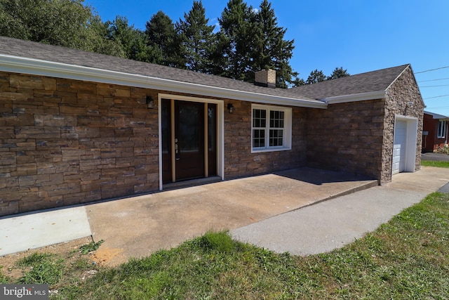 view of exterior entry with a garage and a patio area