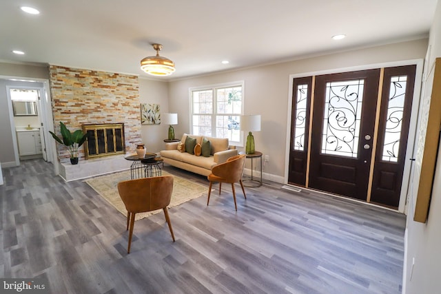 foyer entrance featuring ornamental molding, hardwood / wood-style floors, and a large fireplace