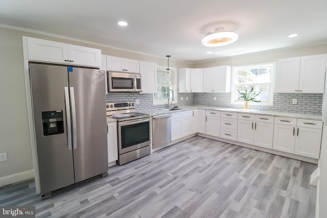 kitchen featuring appliances with stainless steel finishes, white cabinetry, backsplash, and light hardwood / wood-style floors