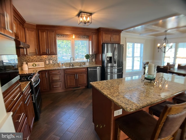 kitchen with appliances with stainless steel finishes, light stone counters, dark hardwood / wood-style flooring, a notable chandelier, and a kitchen bar