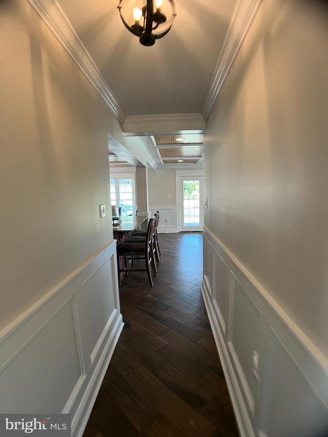 hallway featuring crown molding, dark wood-type flooring, and an inviting chandelier