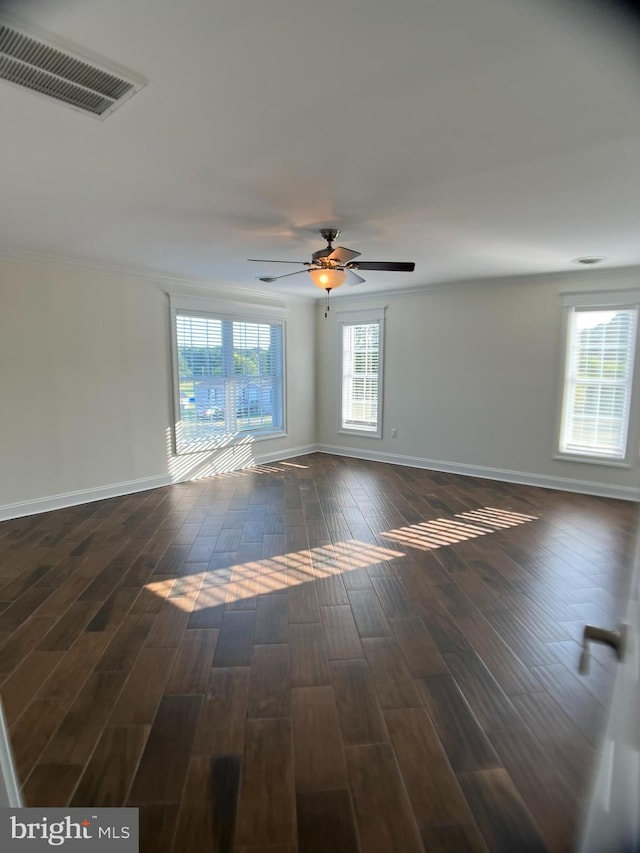 empty room with ceiling fan, a wealth of natural light, and dark hardwood / wood-style flooring