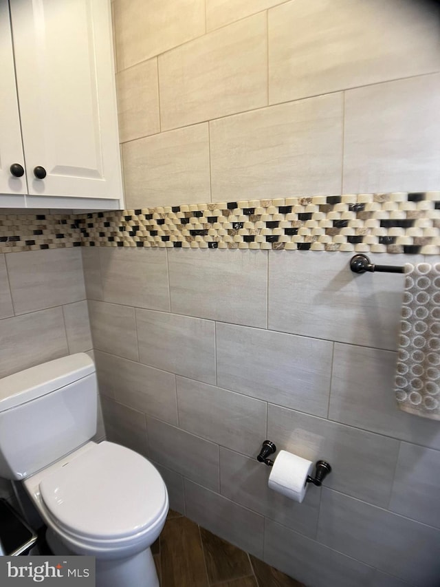 bathroom with tile walls, toilet, and hardwood / wood-style flooring