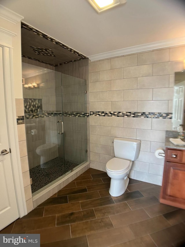 bathroom featuring vanity, toilet, tile walls, and a shower with shower door