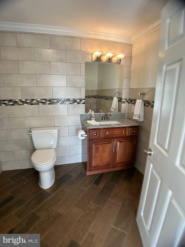 bathroom with tile walls, toilet, ornamental molding, and vanity