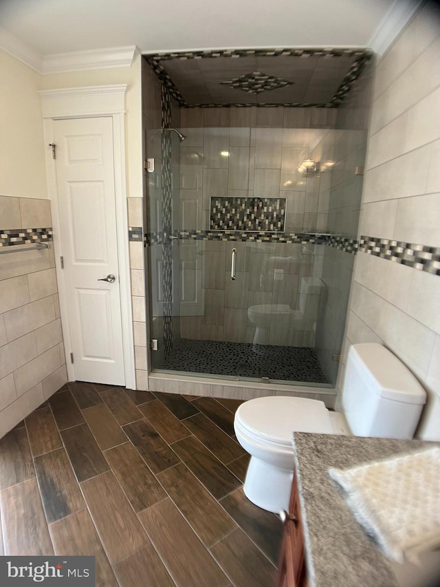 bathroom with toilet, an enclosed shower, crown molding, vanity, and tile walls