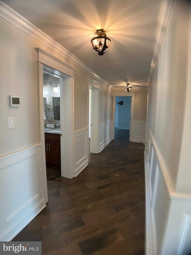 hallway with crown molding, dark wood-type flooring, and a chandelier