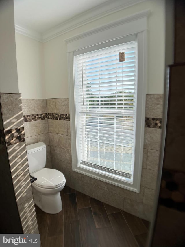 bathroom with crown molding, tile walls, toilet, and hardwood / wood-style flooring