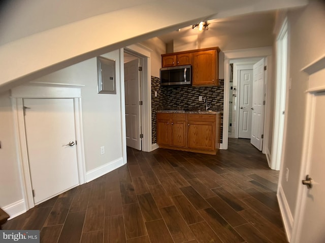 kitchen with stone countertops, electric panel, sink, decorative backsplash, and dark wood-type flooring