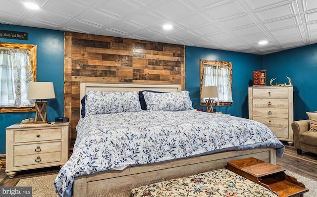 bedroom featuring recessed lighting, wood walls, an ornate ceiling, and wood finished floors